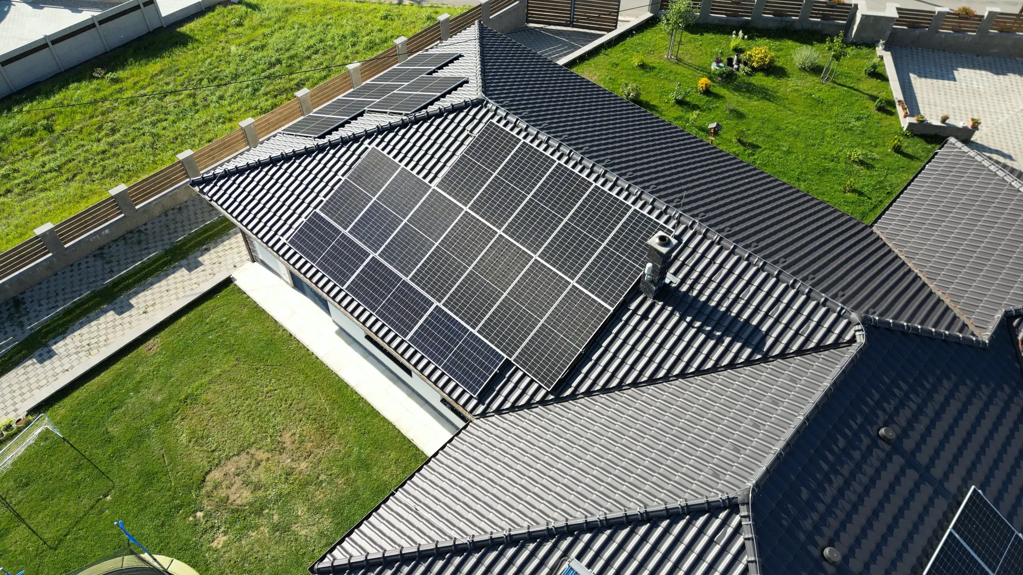 Letecký pohled na rodinný dům s fotovoltaickými panely na tmavé taškové střeše