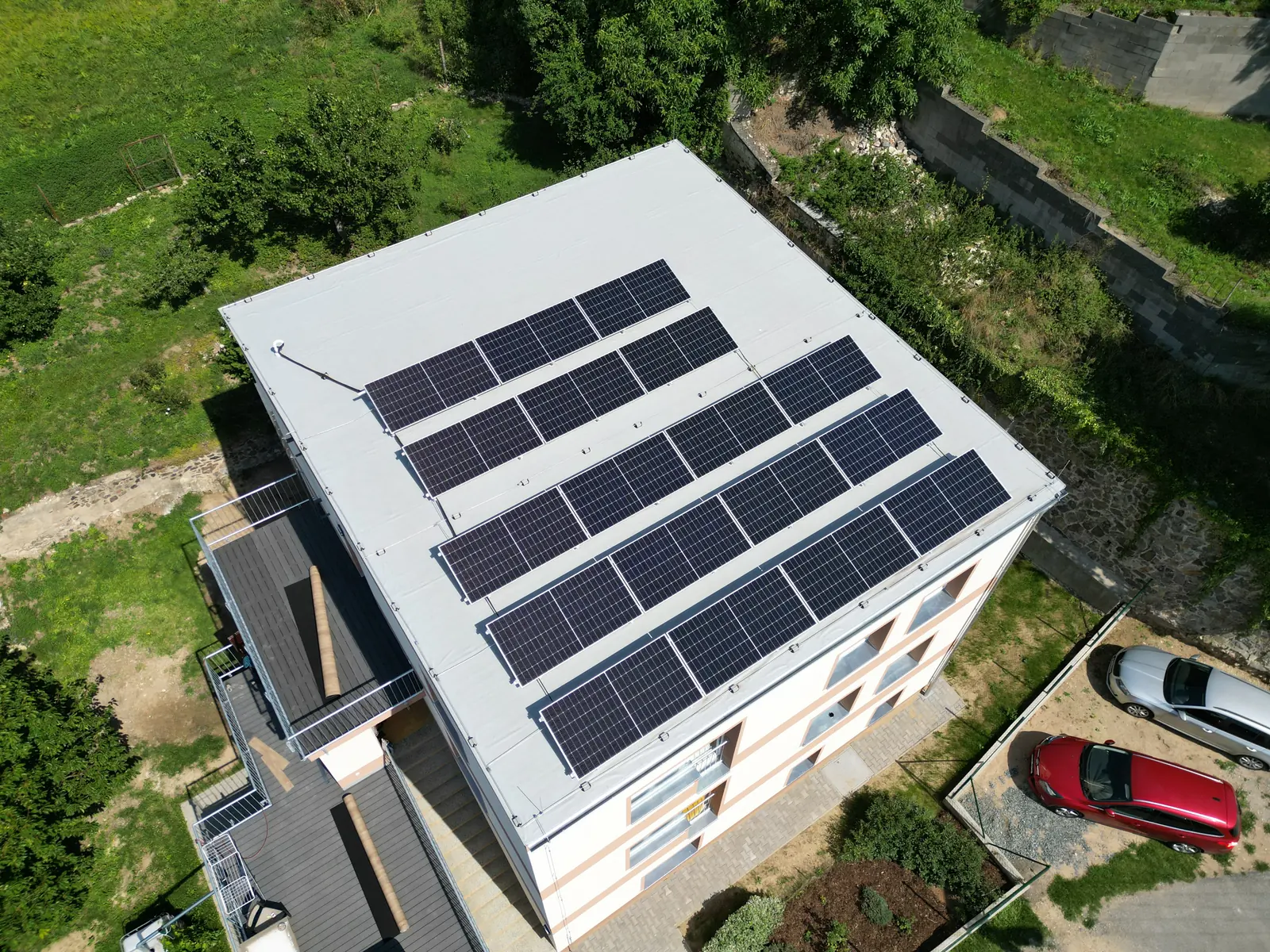Letecký pohled na bytový dům s fotovoltaickými panely na ploché střeše