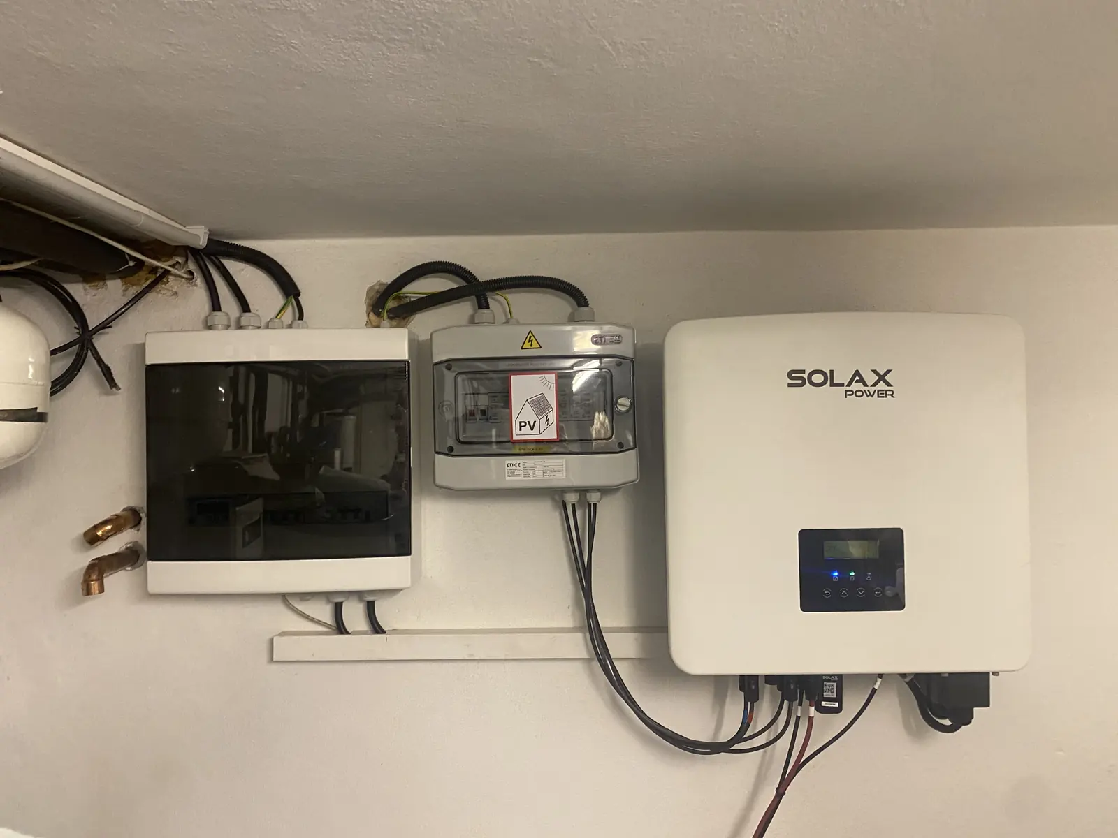 Střídač SolaX a rozvaděč fotovoltaiky na zdi technické místnosti